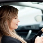 Beautiful businesswoman sending a text while driving