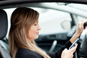 Beautiful businesswoman sending a text while driving